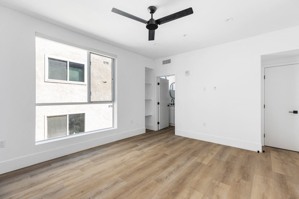 an empty room with a large window and a ceiling fan