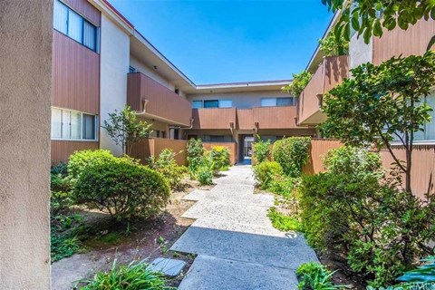 the courtyard of an apartment building with a walkway and plants