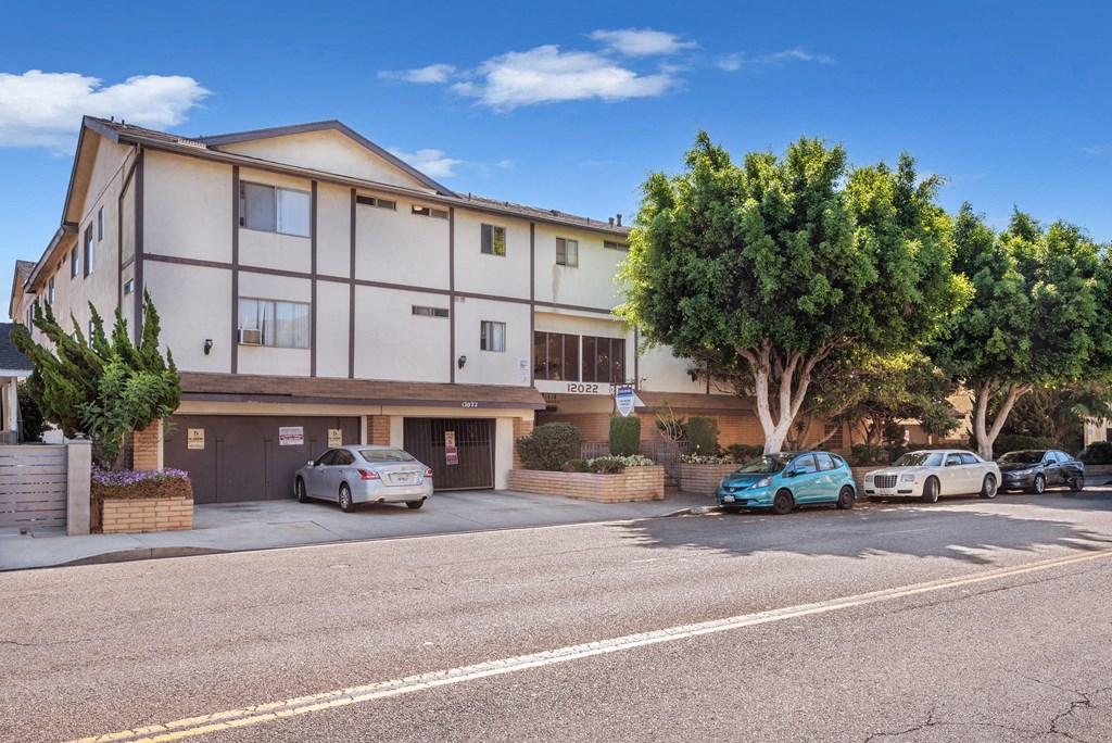 an apartment building on a street with cars parked in front