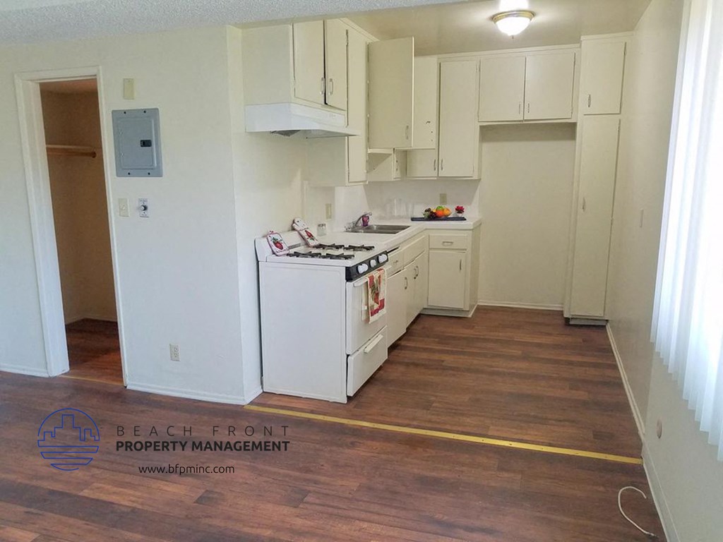 an empty kitchen with white cabinets and a wood floor