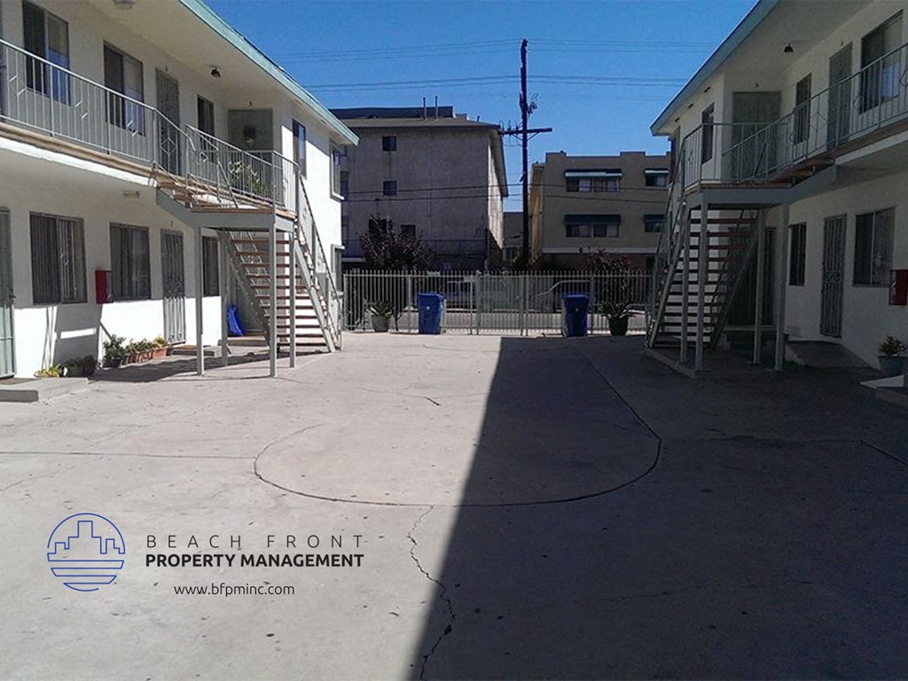 a city street with buildings and stairs and a shadow on the ground