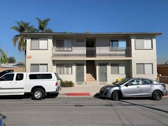 an apartment building with two cars parked in front of it