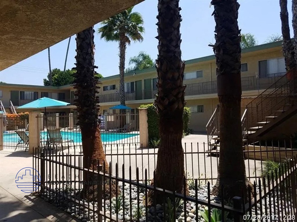 a pool with palm trees and a wrought iron fence