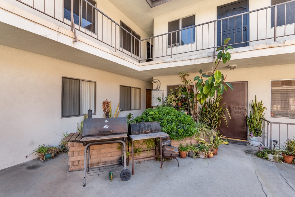 an outdoor patio with a barbecue grill and plants