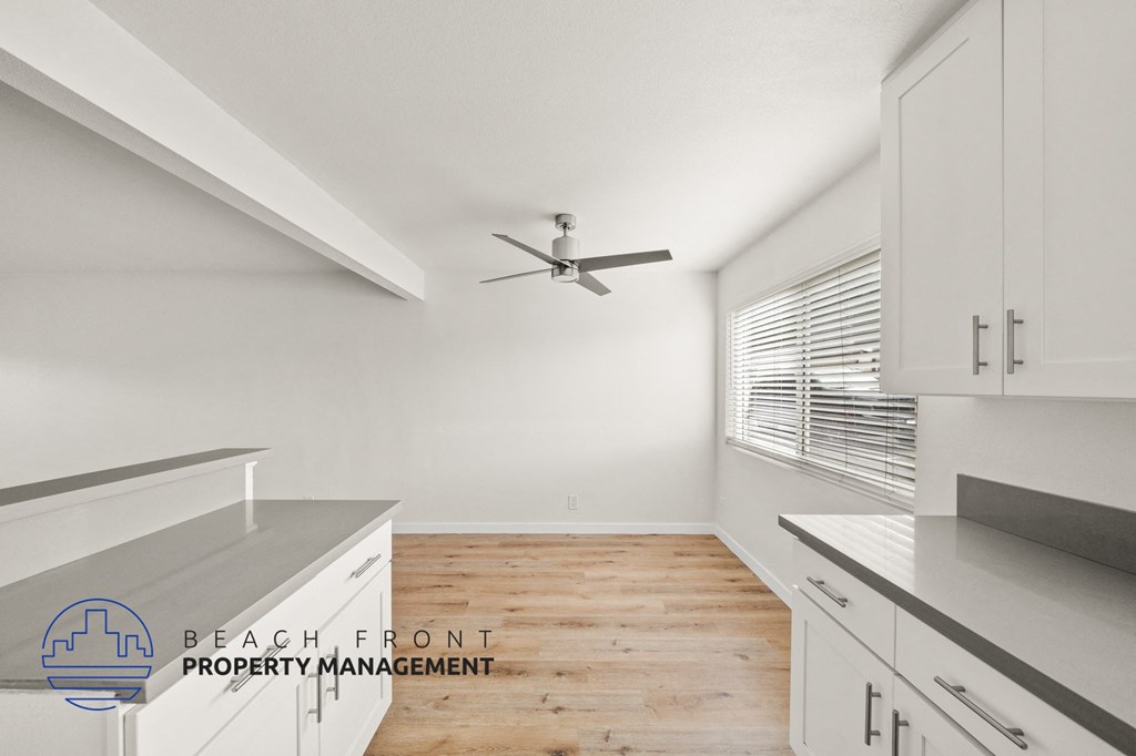 A kitchen with a ceiling fan and wooden flooring.
