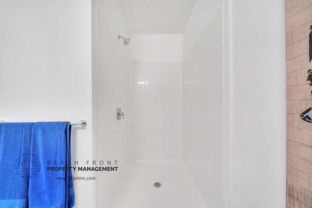 a white shower in a bathroom with blue towels