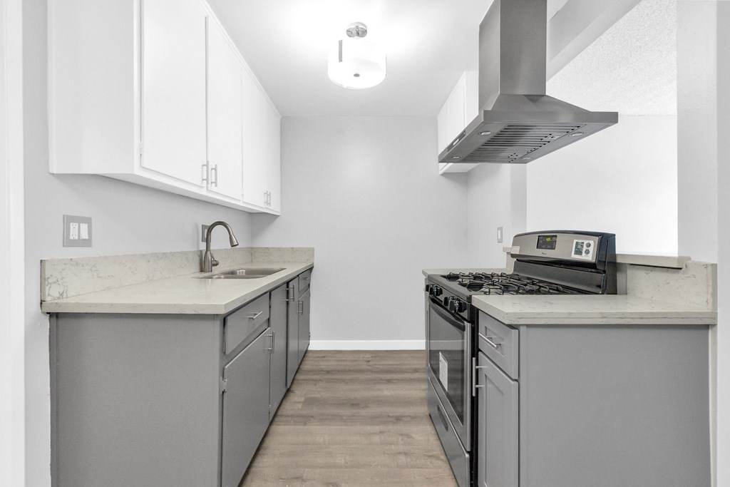 an empty kitchen with stainless steel appliances and white cabinets