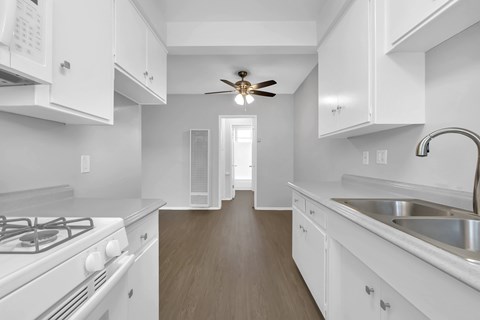 a kitchen with white cabinets and white appliances and a ceiling fan
