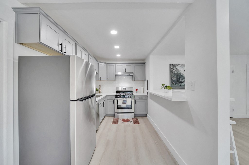 a renovated kitchen with white cabinets and stainless steel appliances