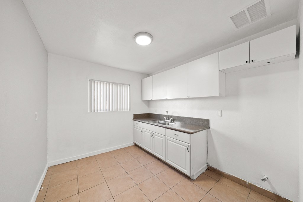 an empty kitchen with white cabinets and a sink and a counter