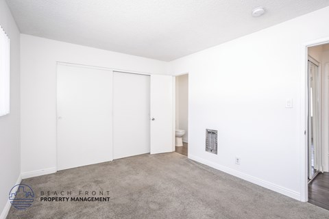 A white bedroom with a carpeted floor and a window.