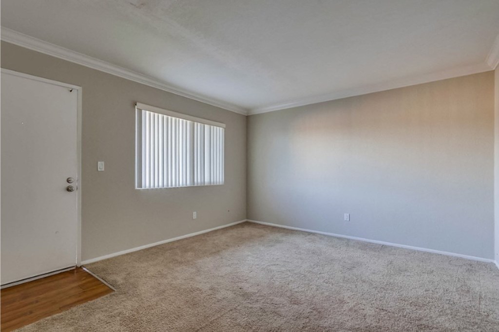 an empty living room with white walls and a window