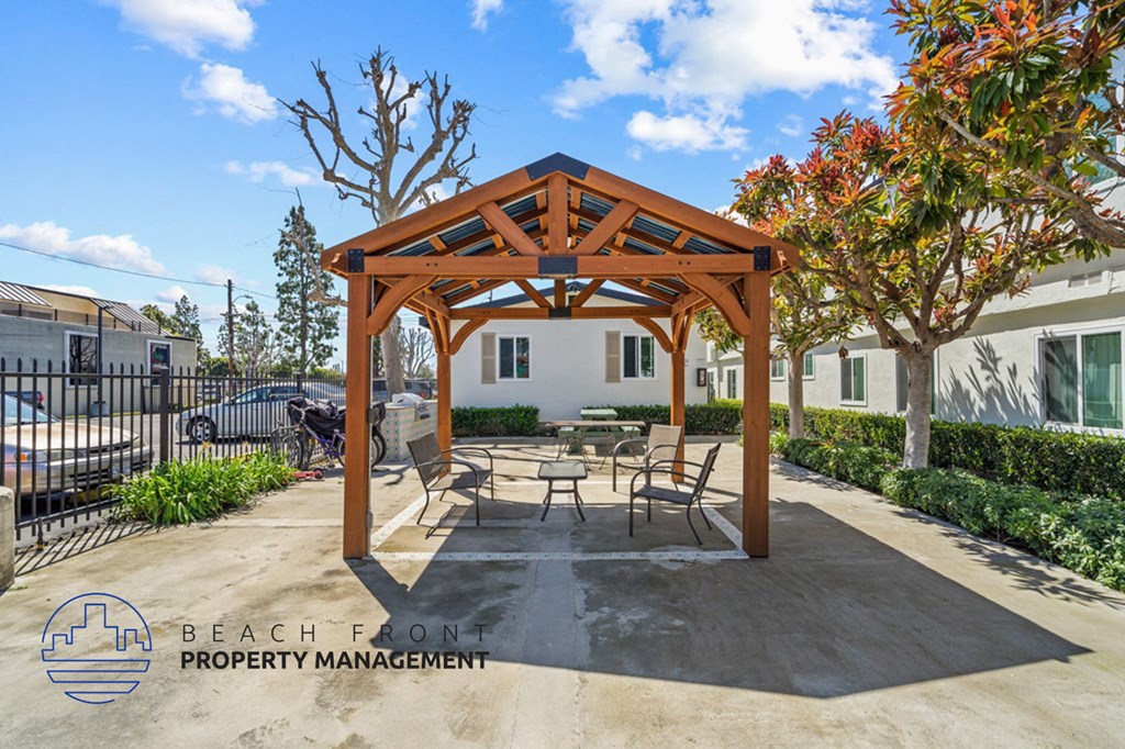 a patio with a picnic table and chairs under a wooden pavilion