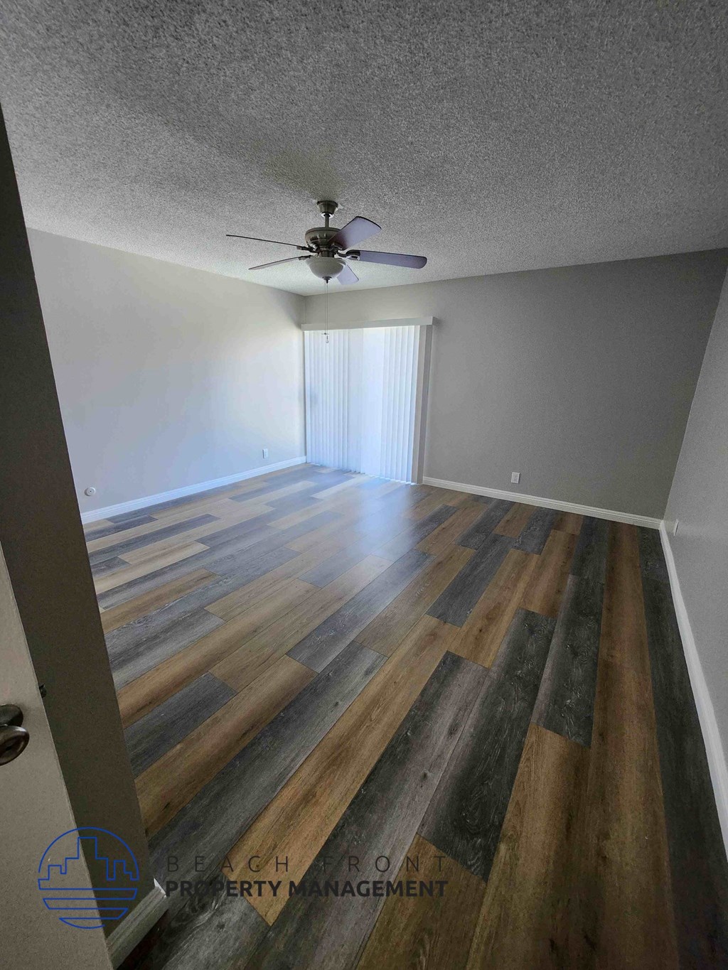 A room with wooden flooring and a ceiling fan.