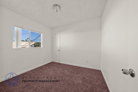 A room with a window showing a view of a building and trees outside.