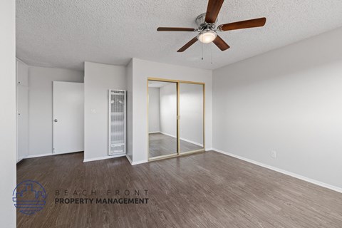 a living room with a ceiling fan and a mirrored closet