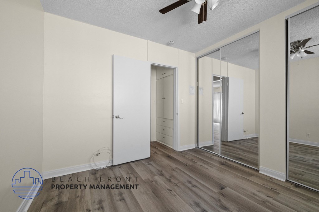 a bedroom with white walls and mirrored closet doors