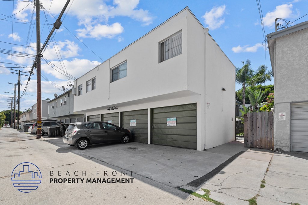 a white building with a garage and a car parked in front of it
