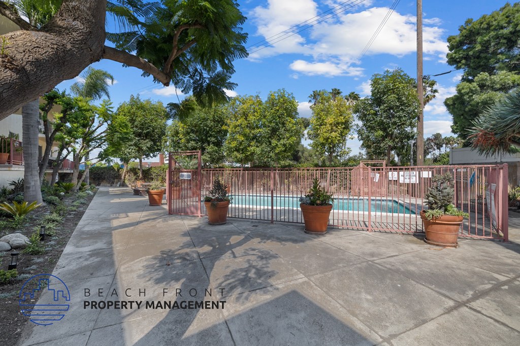 A pool surrounded by a fence and potted plants.