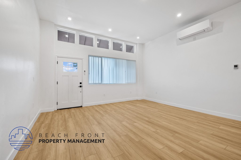 a living room with white walls and wooden floors and a white door