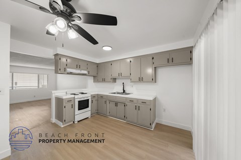 A kitchen with a ceiling fan and a logo for Beach Front Property Management.