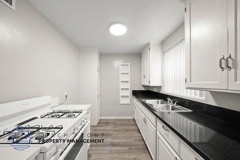A modern kitchen with a white stove and black countertops.