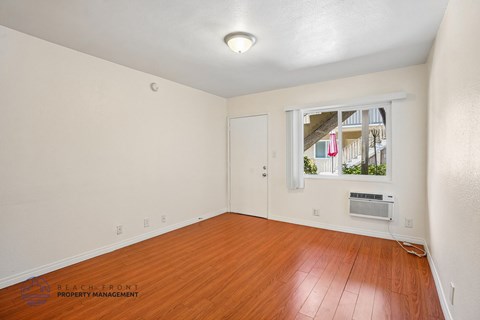 A room with wooden floors and a window showing a view of a building.