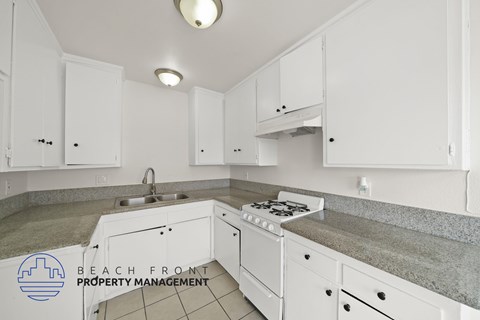 A kitchen with white cabinets and a stove top oven.