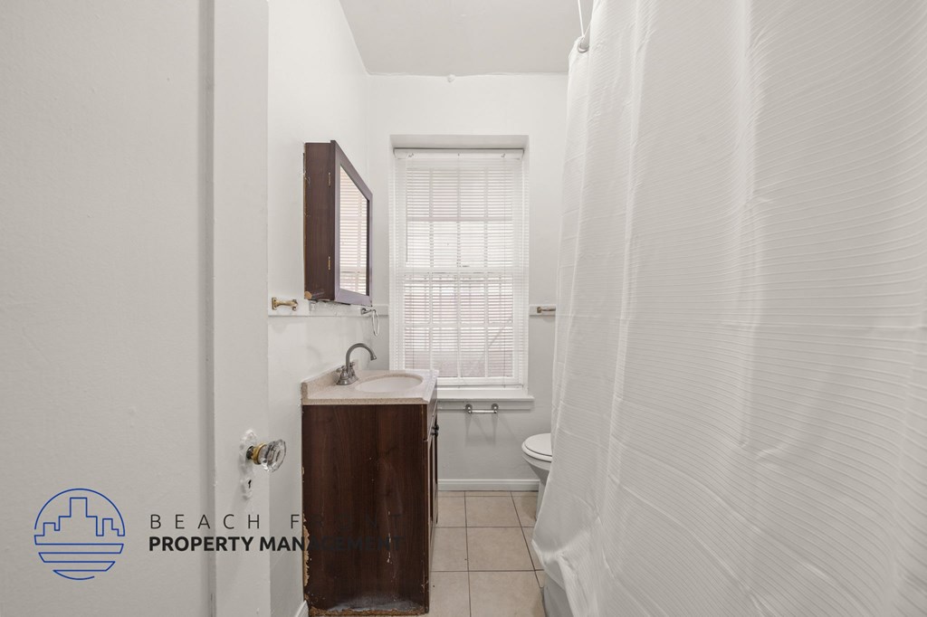 A small bathroom with a toilet, sink, and window.