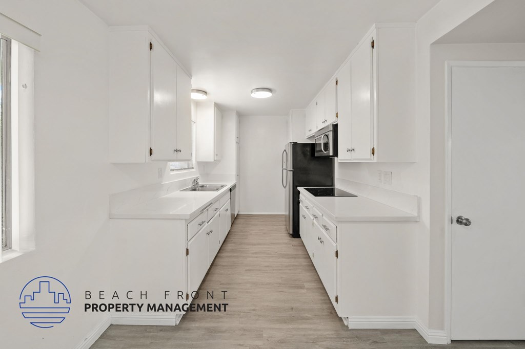 A kitchen with white cabinets and a black refrigerator.