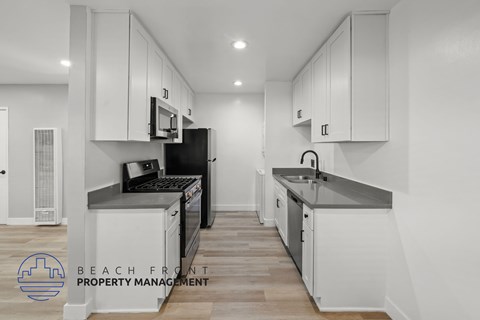 A kitchen with white cabinets and a black refrigerator.