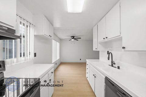 A modern kitchen with white cabinets and a wooden floor.