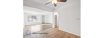 A spacious room with a ceiling fan and a logo for Beach Front Property Management.