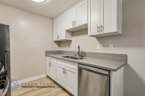 A kitchen with white cabinets and a stainless steel dishwasher.
