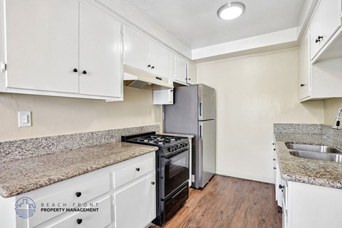 A kitchen with white cabinets and a granite countertop.