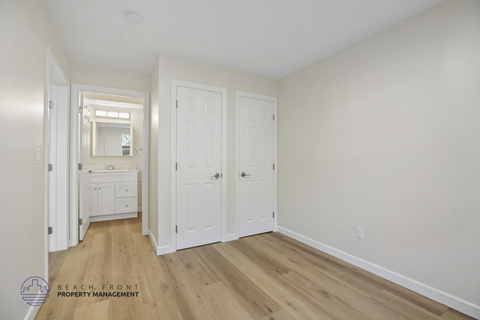 A white bedroom with a dresser and a mirror.