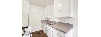 A kitchen with white cabinets and a stove top oven.