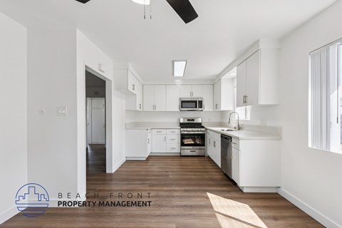 A spacious kitchen with white cabinets and a wooden floor.