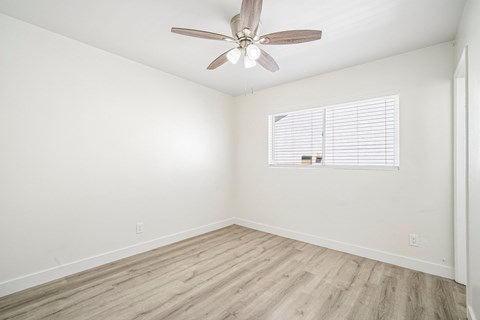 A room with a ceiling fan and a window with blinds.