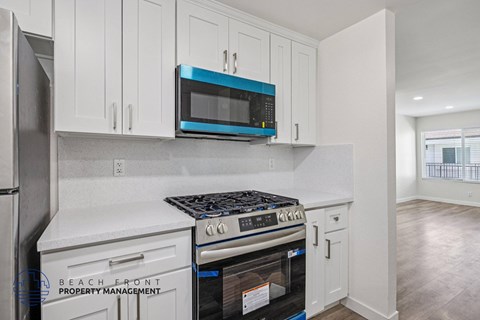 A kitchen with white cabinets and a blue microwave.