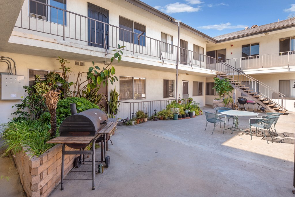 a patio with tables and chairs and a grill