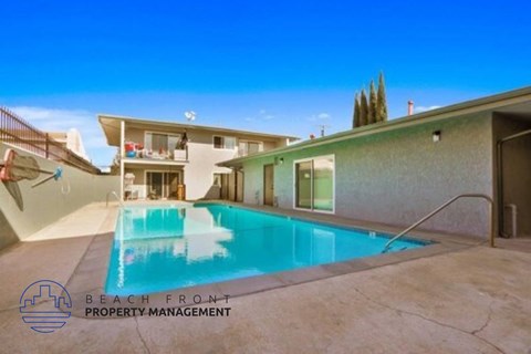 A pool in a backyard with a building in the background.