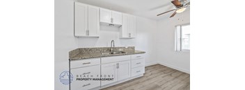 A kitchen with white cabinets and a granite countertop.