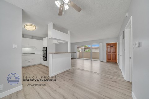 an open kitchen and living room with white cabinets and wood flooring