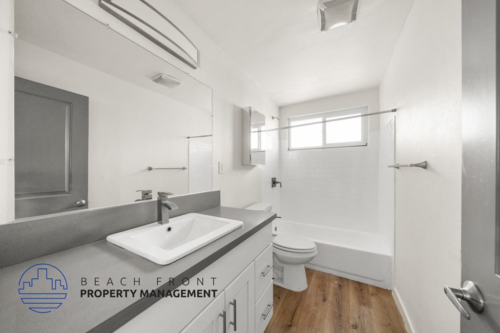 A bathroom with a sink, toilet, and mirror.
