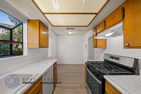 a kitchen with wooden cabinets and a stove and a window
