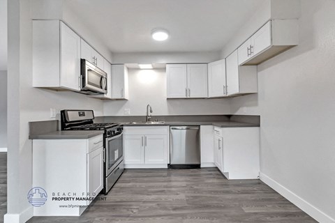 an empty kitchen with white cabinets and a stove and a microwave