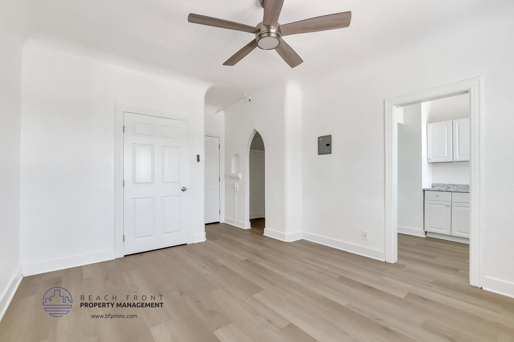 a living room with white walls and a ceiling fan