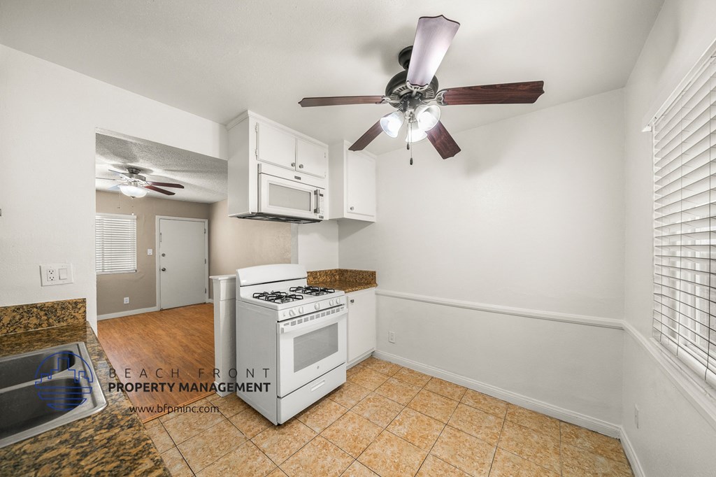 a kitchen with a stove and a ceiling fan