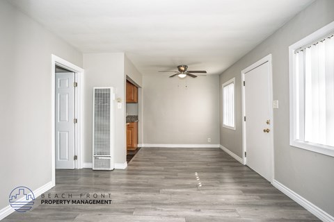 A spacious room with a ceiling fan and wooden flooring.